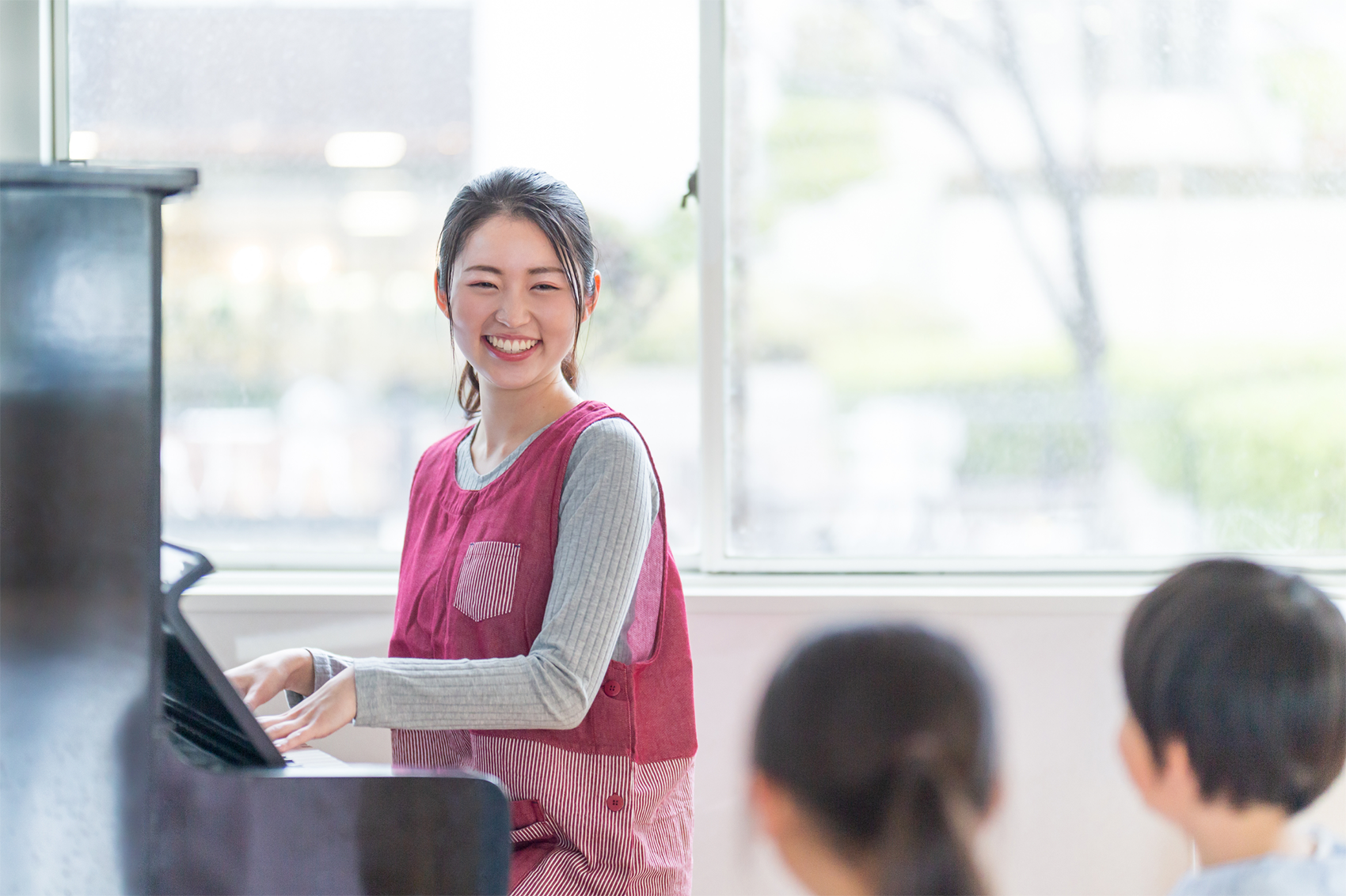 ピアノを弾きながら笑顔で子どもたちと接する保育士