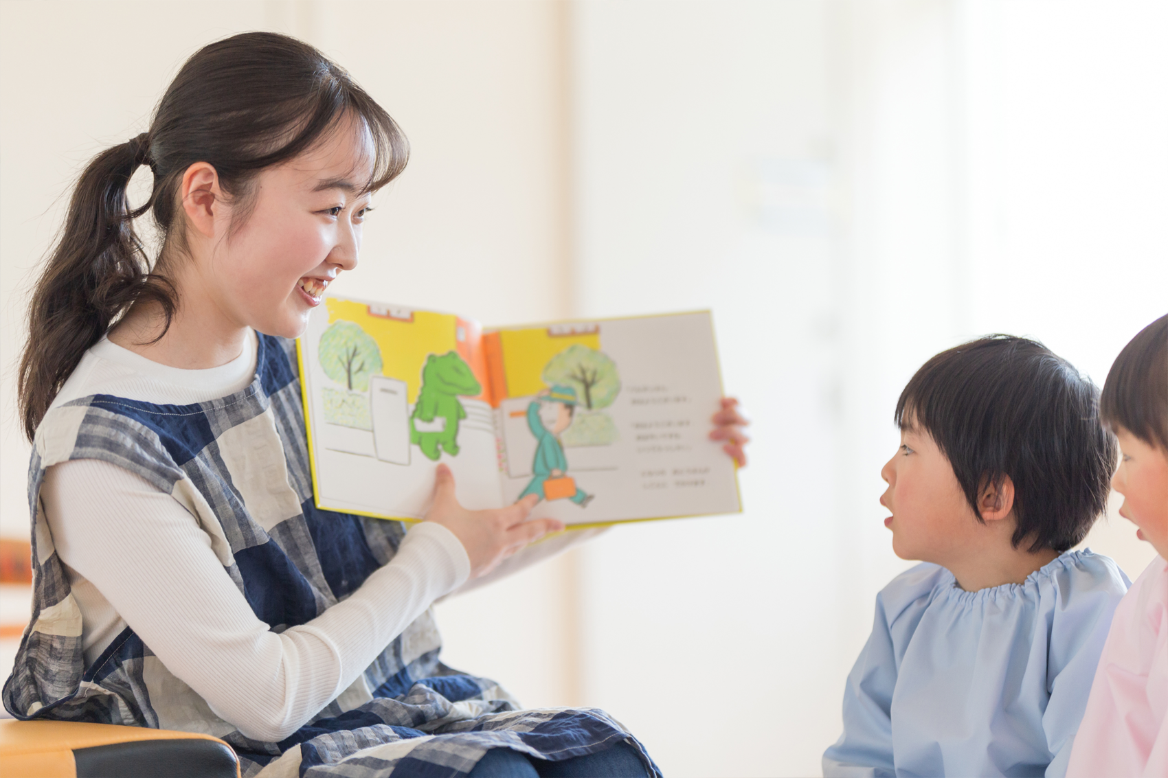絵本の読み聞かせをする保育士と聞き入る子どもたち